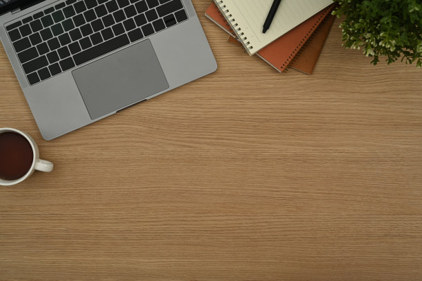 上图是笔记本电脑、咖啡杯、笔记本和木桌上的盆栽。带有复制空间的俯视图。图片下载