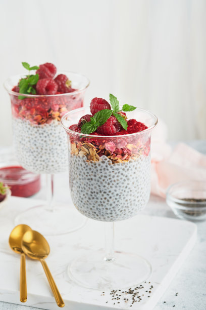 贾布丁。健康的香草奇亚布丁在玻璃与新鲜的覆盆子和薄荷在白色的背景。素食健康的早餐。图片下载