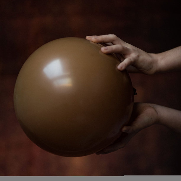 孩子们的玩具是各种各样的幻想，梦想把孩子的想象力带入了梦幻的不真实的游戏世界，照片中女孩的手拿着一个棕色的气球图片下载