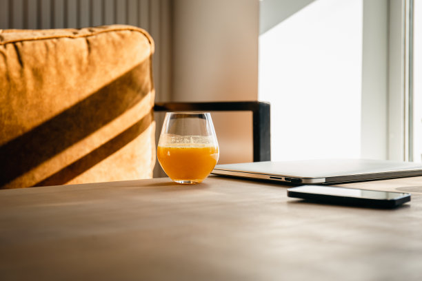 早上在笔记本电脑旁边的桌子上喝一杯橙汁。图片下载