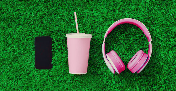 粉色耳机，黑色空白复制空间屏幕智能手机，一杯果汁在绿色的草地背景，俯视图，平躺图片下载