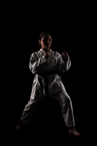年轻的女孩练习空手道。在黑色背景下穿着和服的孩子。图片下载