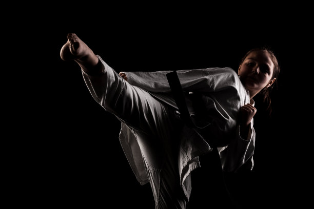 年轻的女孩练习空手道。在黑色背景下穿着和服的孩子。图片下载