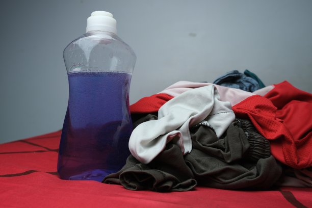 脏衣服旁边的一瓶液体洗涤剂，洗衣的概念图片下载