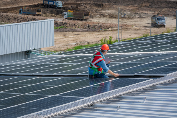 工程师在工厂屋顶上工作并检查太阳能电池板。图片下载