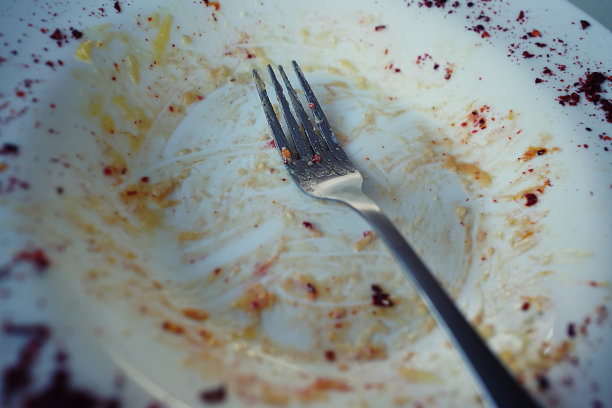 空的白色未洗盘子，食物屑和金属叉子特写图片下载