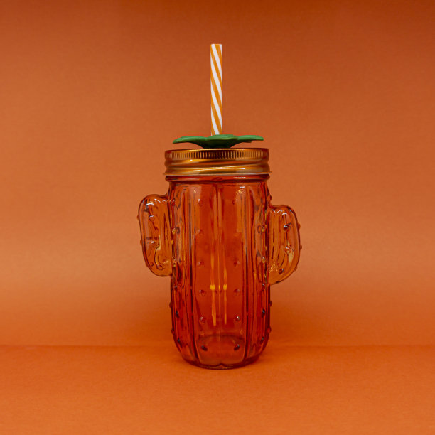 橙色仙人掌设计的玻璃杯，在橙色的背景上图片下载