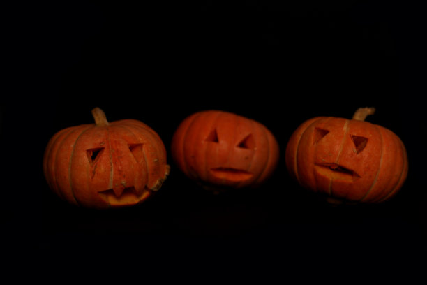 令人毛骨悚然的概念-三个南瓜灯孤立在黑色背景。映像包含复制空间图片下载