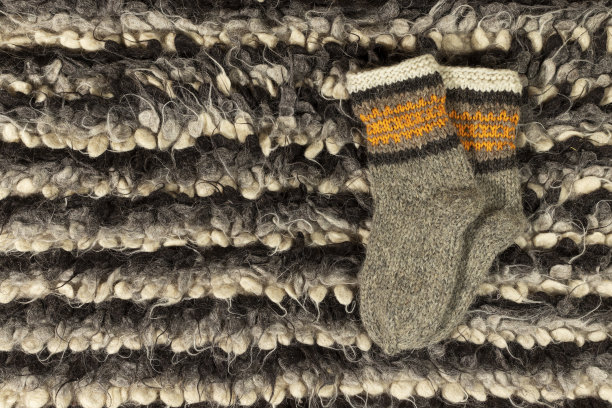 暖暖的羊毛袜子在针织地毯上的特写。图片下载