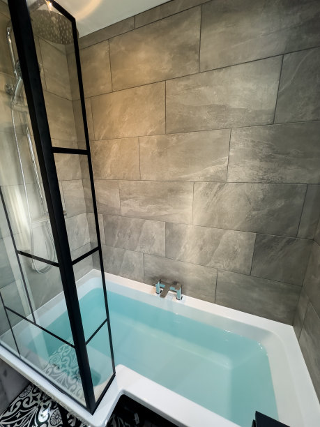 一个现代化的小浴室，有深色的水池和镜子。灰色瓷砖，镀铬淋浴和水龙头。淋浴屏幕上的黑色细节图片下载