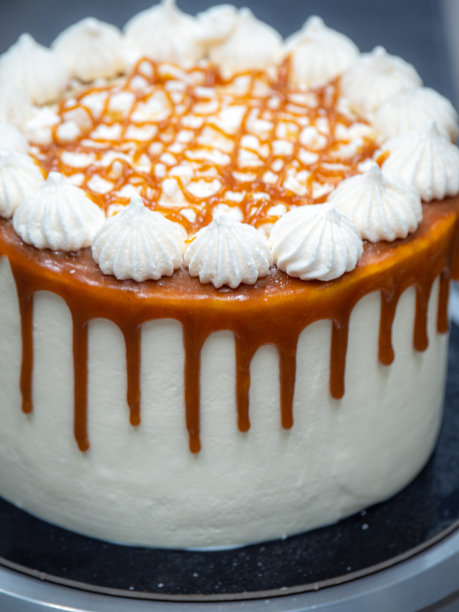 厨师手工制作蛋糕顶部的蛋白糖霜上滴着咸焦糖图片下载