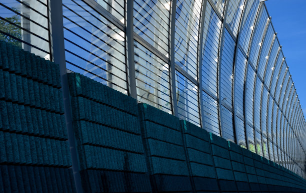 隔音墙的条纹玻璃在高速公路大桥上嵌入金属梁，在街道上。用压力螺丝固定窗户。多孔的石块在道路上方弯曲倾斜，对角线，向上攀升图片下载