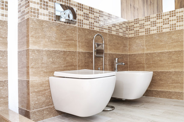 在一个现代化的浴室里，白色陶瓷马桶靠在浅棕色的墙上图片下载