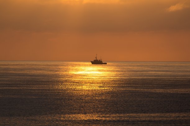 在泰国的日落时分，一艘船横在大海中央图片下载