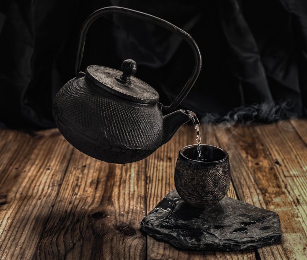 浅聚焦特写镜头一个茶壶在空气中倒热水到一杯茶图片下载