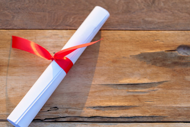 文凭与红色蝴蝶结放置在木bakground图片下载