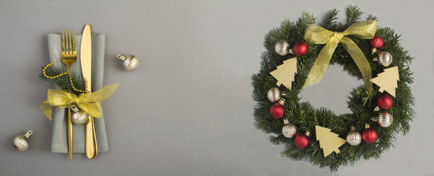 圣诞节的餐桌摆设和戒指或花环，在灰色的背景上有红色和金色的球。副本的空间。图片下载