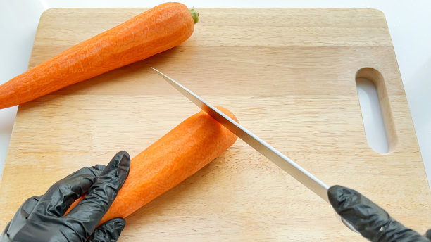 用锋利的刀在木板上切掉胡萝卜顶部的俯视图。图片下载