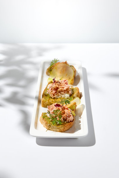 美学构成与蟹意式烤面包在白色背景与阴影从花。意大利烤面包配螃蟹、牛油果和奶酪，夏日美食。优雅的菜单的概念。图片下载