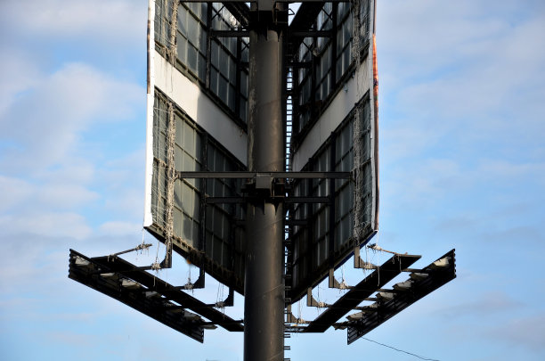 路边一根黑色柱子上的广告横幅广告牌。拉伸帆布塑料篷布与广告信息系在后面的字符串。付房租的黑色巨型广告牌图片下载