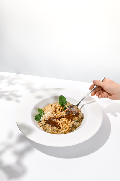 牛肉脸颊与妇女手握勺子。吃的食物。女手红烧牛肉。女人在餐馆里吃肉。趋势菜单的概念。图片下载