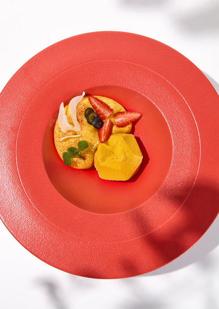 白色底色上现代风格的黄色慕斯蛋糕。百香果蛋糕配芒果慕斯和浆果。酸奶蛋糕与百香果在餐厅盘轻慕斯甜点图片下载