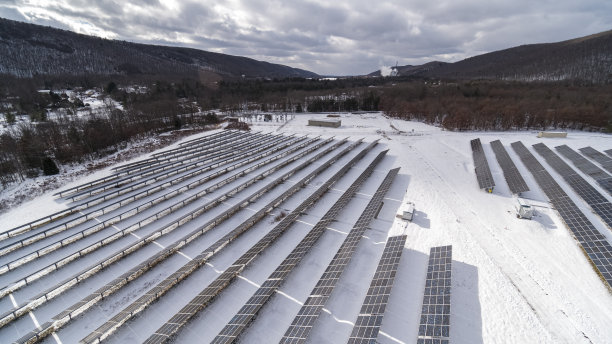 宾夕法尼亚州阿巴拉契亚山脉的大型太阳能发电厂，在一个下雪后的晴朗冬日。图片下载