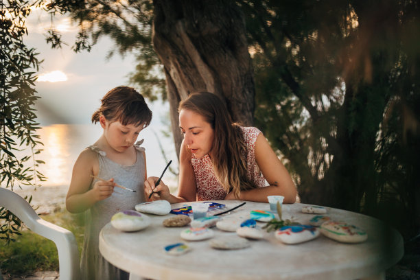 妈妈教她可爱的小女儿在石头上画画图片下载