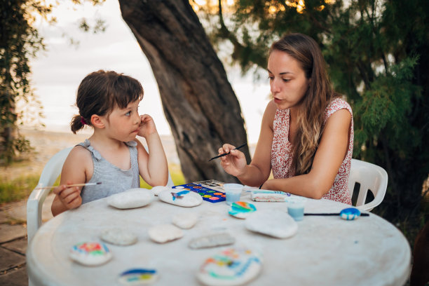 一位母亲教她的女儿在石头上画画图片下载