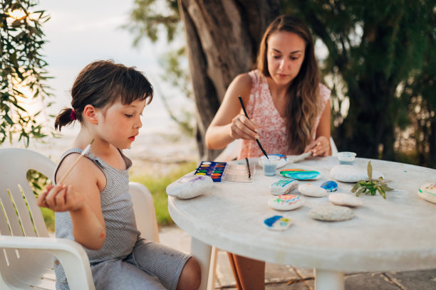 一个可爱的小女孩和她的妈妈用水彩装饰石头图片下载