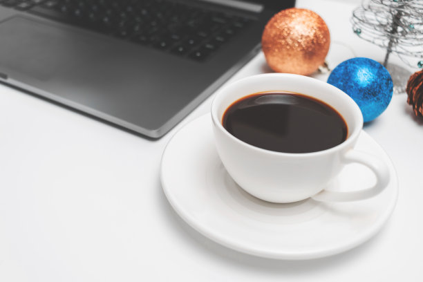 咖啡杯在白色的桌子与笔记本电脑和圣诞装饰，近距离观看图片下载