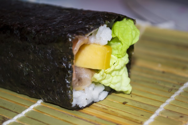 寿司和鱼是扭曲的，而不是切开的。近距离看扭曲的海苔卷。一长卷寿司创建角色。图片下载