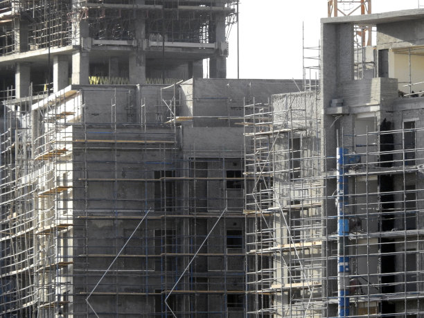 新建住宅楼和高层建筑的建筑工地，有起重机运输重物，在建建筑物的部分选择性聚焦图片下载