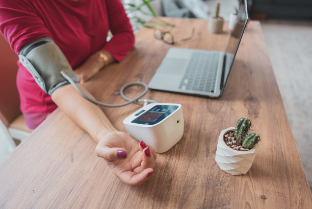 在家工作的妇女调整腕表来检查她的血压图片下载