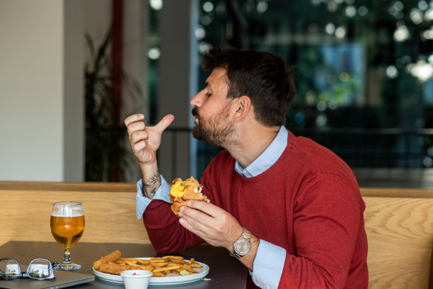 有魅力的商人吃着汉堡舔着手指图片下载