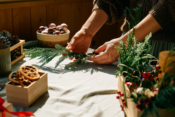 一名妇女用冷杉树枝和干橙子做圣诞安排。女性的双手创造了圣诞手工艺手工装饰。新年的庆祝活动。冬天的假期。图片下载