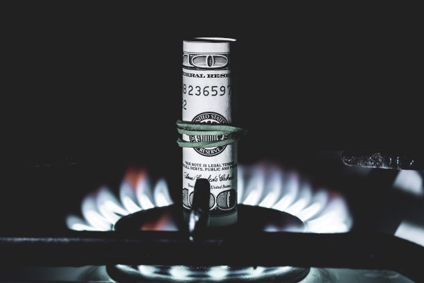 一张100美元的钞票在煤气灶上燃烧的火在黑色背景上，前后背景模糊与散景效果图片下载