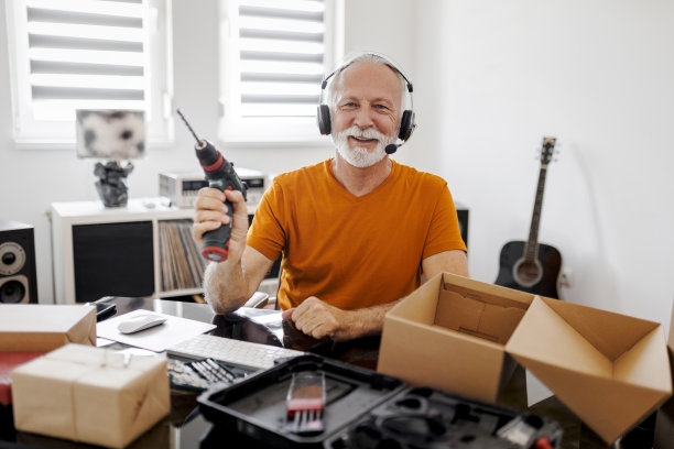 微笑的男性社交媒体技术影响者在家里录制开箱视频图片下载