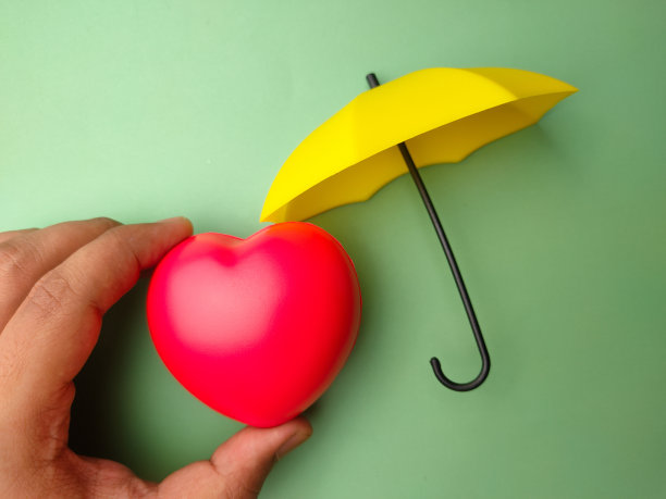 手拿红心和彩色背景的黄伞。图片下载