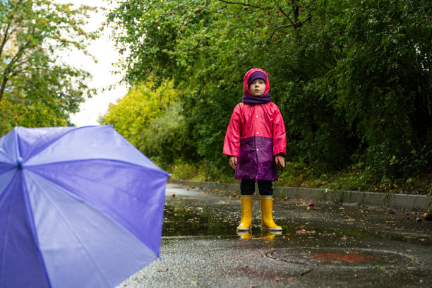 孩子打着伞走在雨中。在户外打着伞的小男孩图片下载