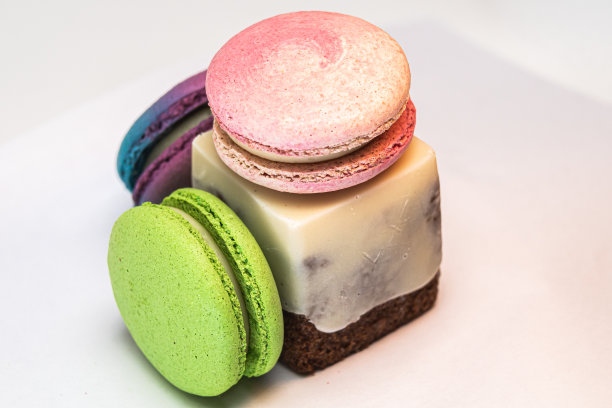 美味的彩色法式马卡龙，白色的背景上有一块蛋糕图片下载