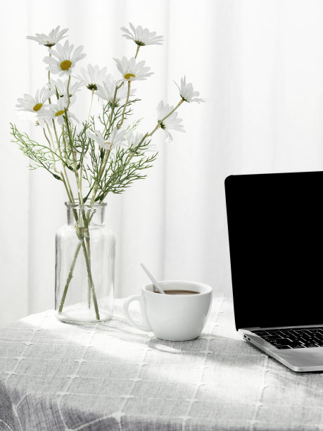 垂直拍摄一台笔记本电脑和一杯咖啡，旁边是一个装满鲜花的花瓶，在室内图片下载