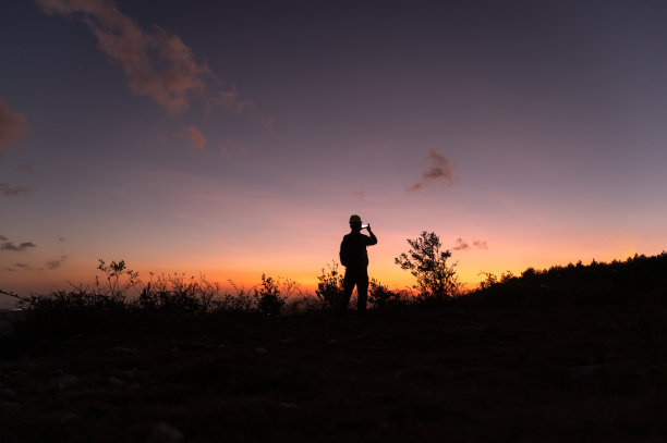 一个人的剪影在红色的夜空下在山上拍照图片下载