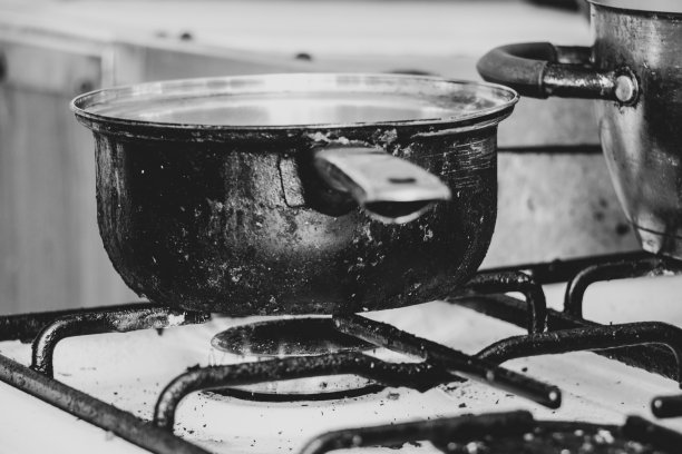 家里厨房的脏煤气炉上立着一只脏锅，在炉子上煮汤，煤气炉图片下载