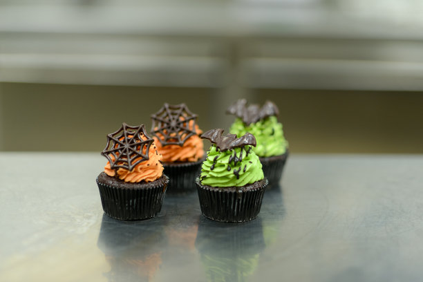 糕点师正在准备手工制作的万圣节绿橙怪兽纸杯蛋糕图片下载
