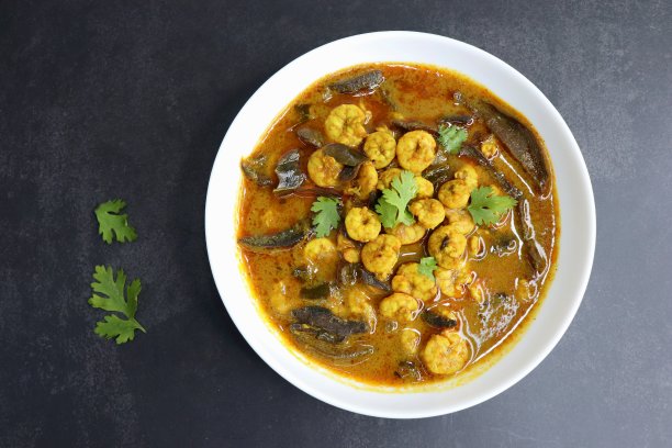 辛辣的咖喱虾。用干芒果和印度香料做成的咖喱虾。配以香菜和黄瓜片。副本的空间。图片下载