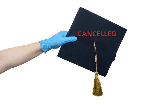 手戴蓝色丁腈外科手套，手持写有“取消”字样的毕业帽图片下载