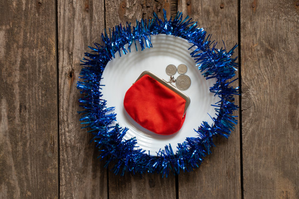 红色的钱包躺在一个白色的盘子装饰新年的彩色丝带在一个木制的背景接近，新年的装饰图片下载