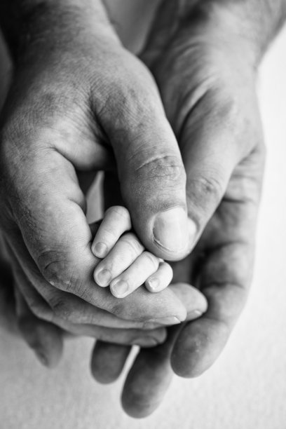 熟睡的新生儿握着父母的手，父母特写。新生儿的小手指。一家人手牵着手。黑白微距摄影家庭和爱情的概念图片下载