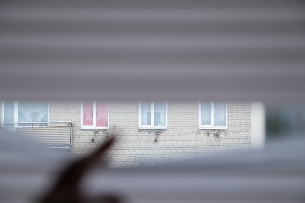 手指放在房子窗户上的百叶窗上，透过百叶窗向窗外看图片下载